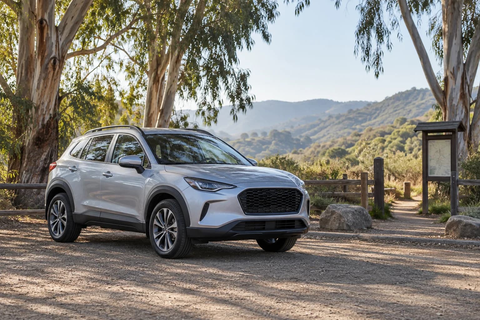 A silver crossover parked beneath eucalyptus trees at a trailhead